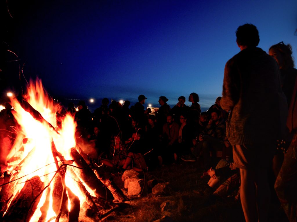 crowd around a campfire on the beach